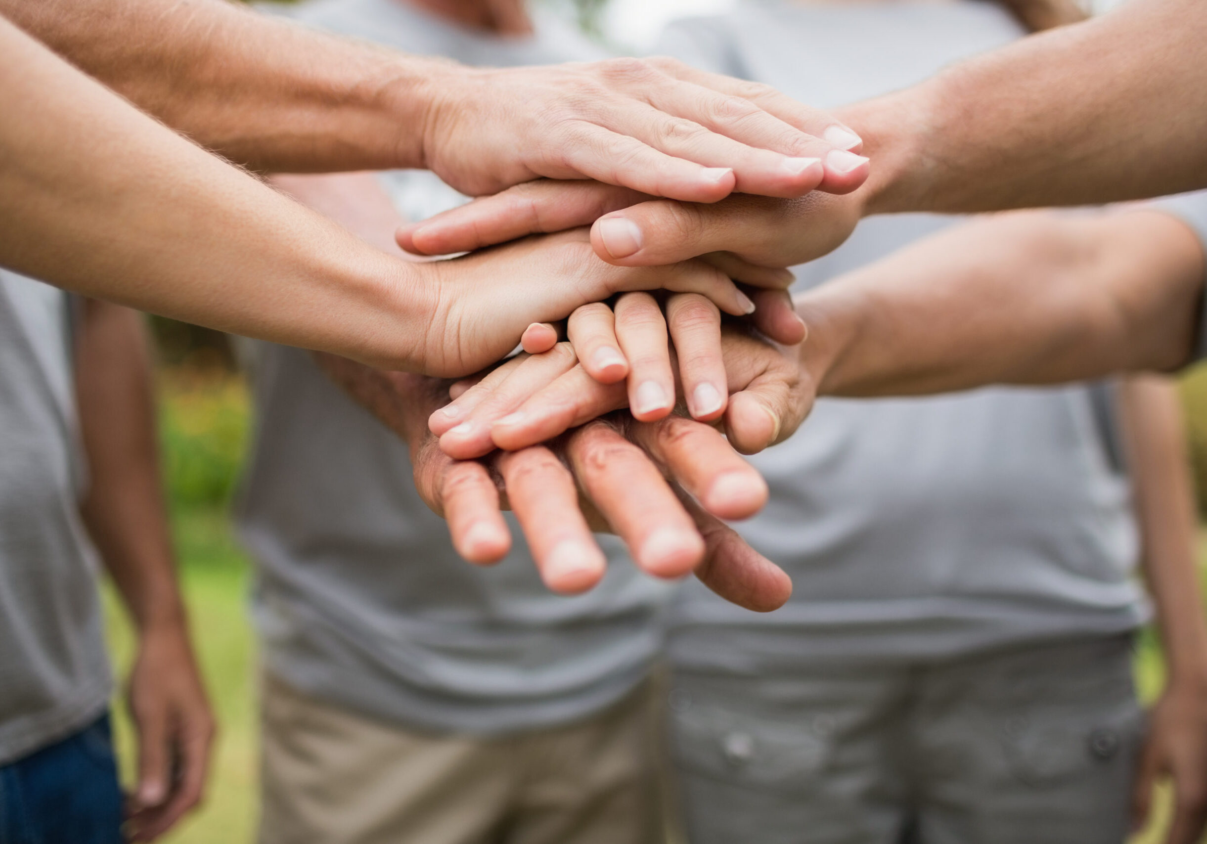 Happy volunteer family putting their hands together on a sunny day